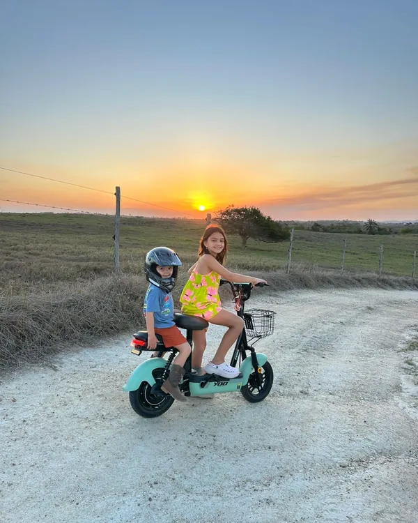 Crianças passeiam numa motinha elétrica ao pôr do sol